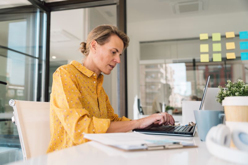 Women with yellow shirt working on a laptop